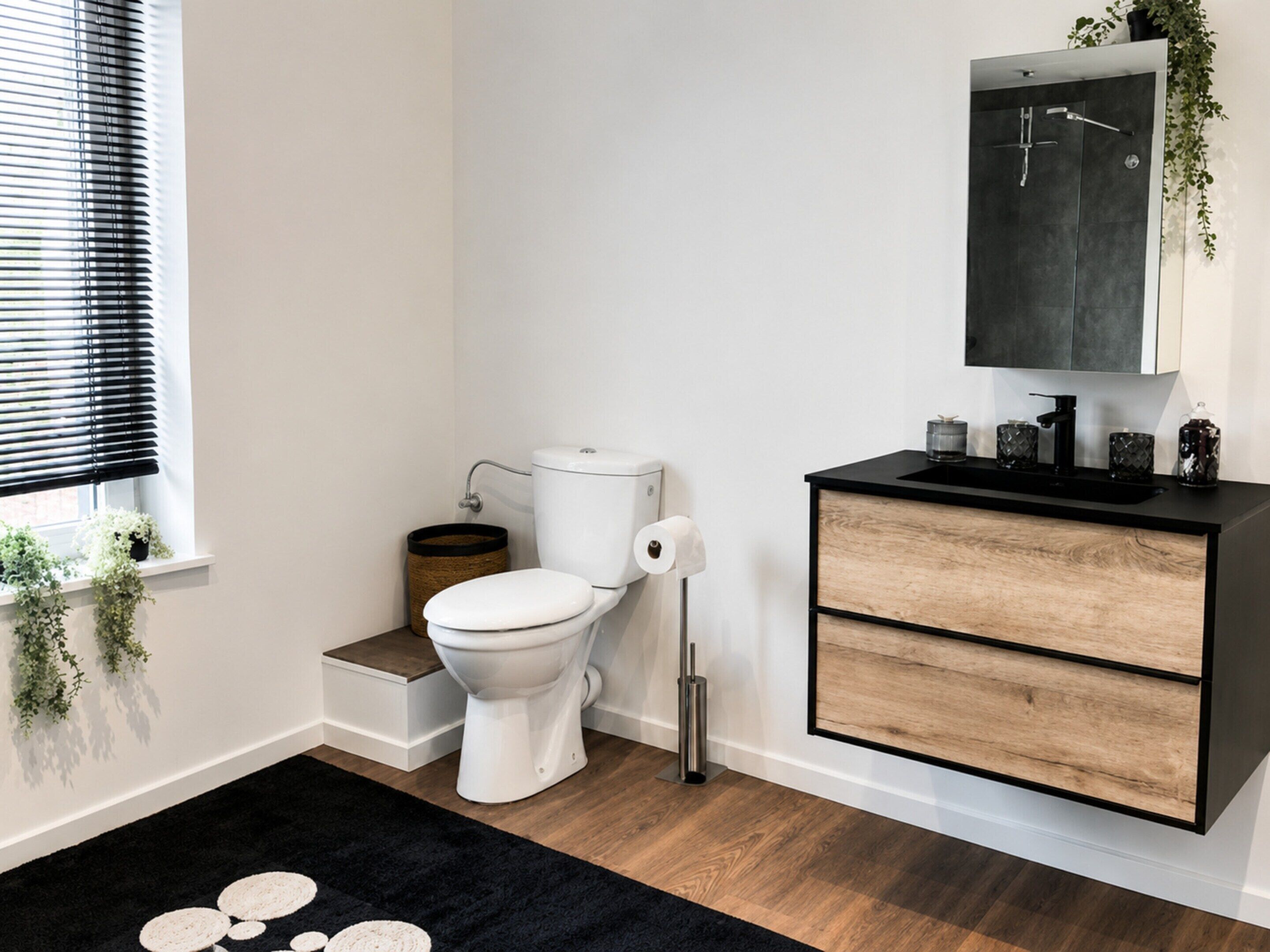 Een moderne badkamer met toilet, wastafel en spiegel.