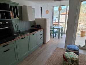 Une cuisine moderne équipée d’un four encastré, d’un évier et d’un réfrigérateur. On y trouve également un coin repas avec une table et des chaises.