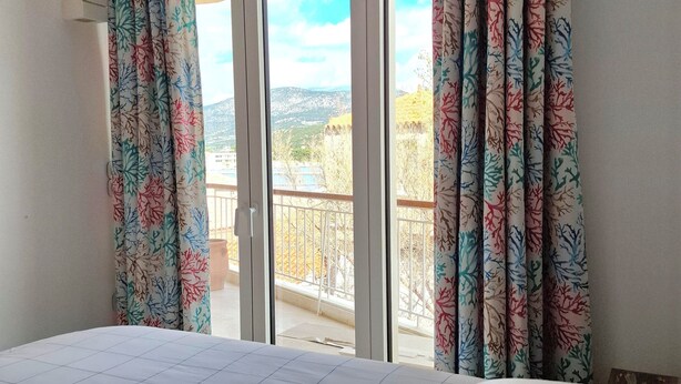 Ein Schlafzimmer mit Bett, Vorhängen und einem Balkon mit Blick.