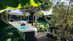 Een hottub op een houten terras met een witte luifel erboven.