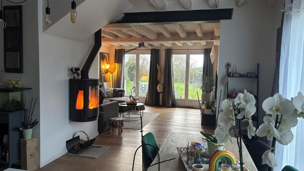 Een gezellige woonkamer met een open haard, een bank en een eethoek met een regenboogdecoratie.