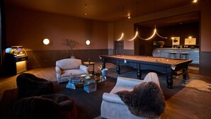 A modern living room with a pool table, comfortable seating, and a bar area.