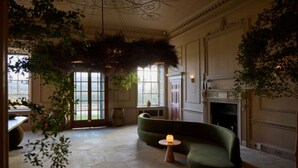 A spacious room with a green sofa, a small round table, and a fireplace.