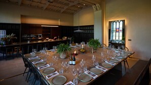 A large dining room with a long table set for a meal, surrounded by chairs.
