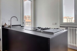 A modern kitchen with a built-in stove, a sink, and a window with a city view. - Hostmate - Milano - Muratori - Porta Romana  (Milano)
