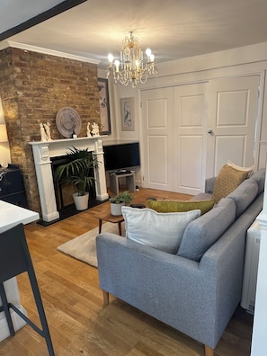 A living room with a fireplace, a television, a sofa, and a chandelier.