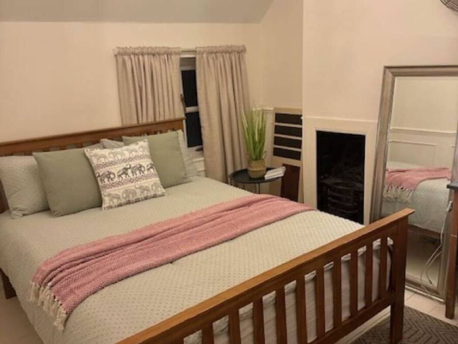 Quarto com cama de madeira, um candelabro, um espelho e uma lareira.