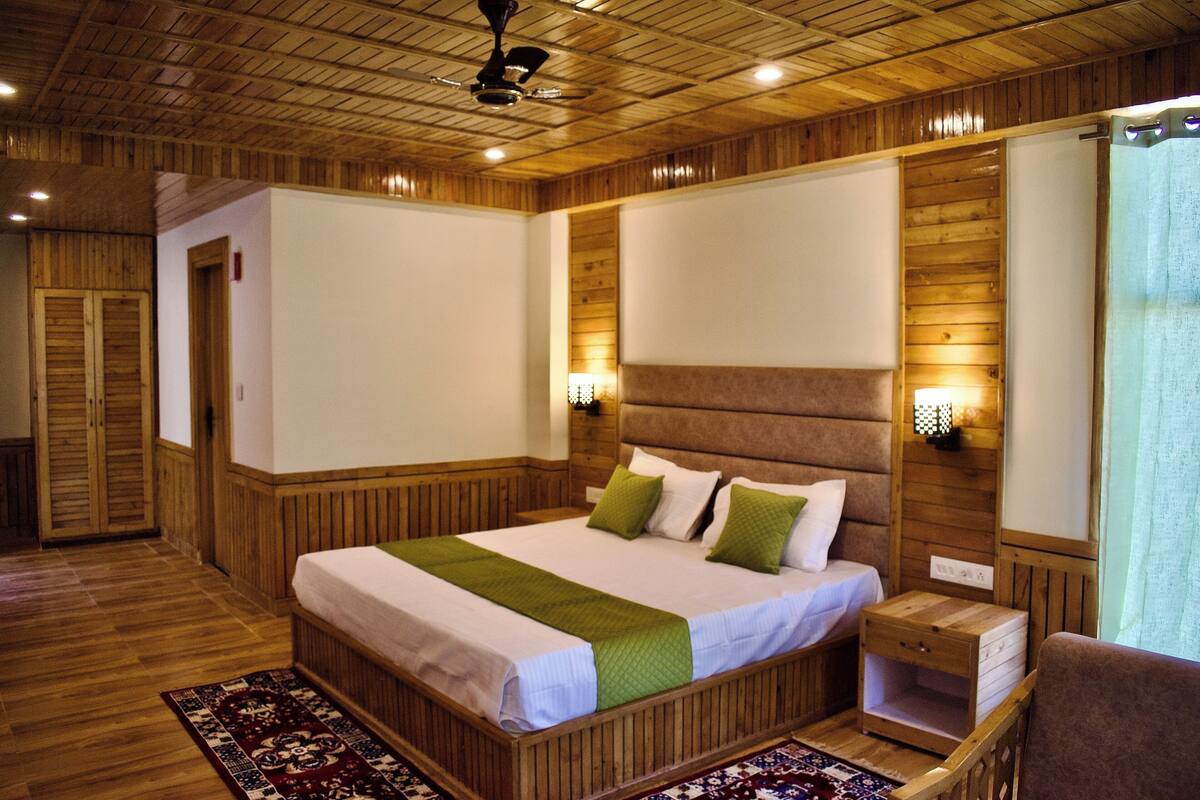 A wooden-paneled bedroom with a large bed, bedside tables, and a nightstand.