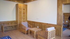 Een kamer met houten meubels, waaronder een bankje, twee stoelen en een tafel.