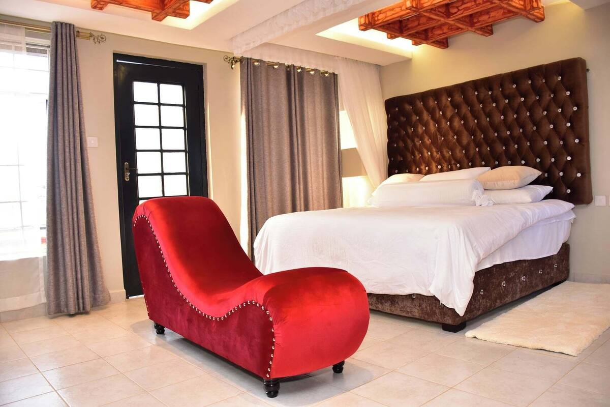 Une chambre à coucher avec un grand lit, un fauteuil rouge et un plafond en bois.