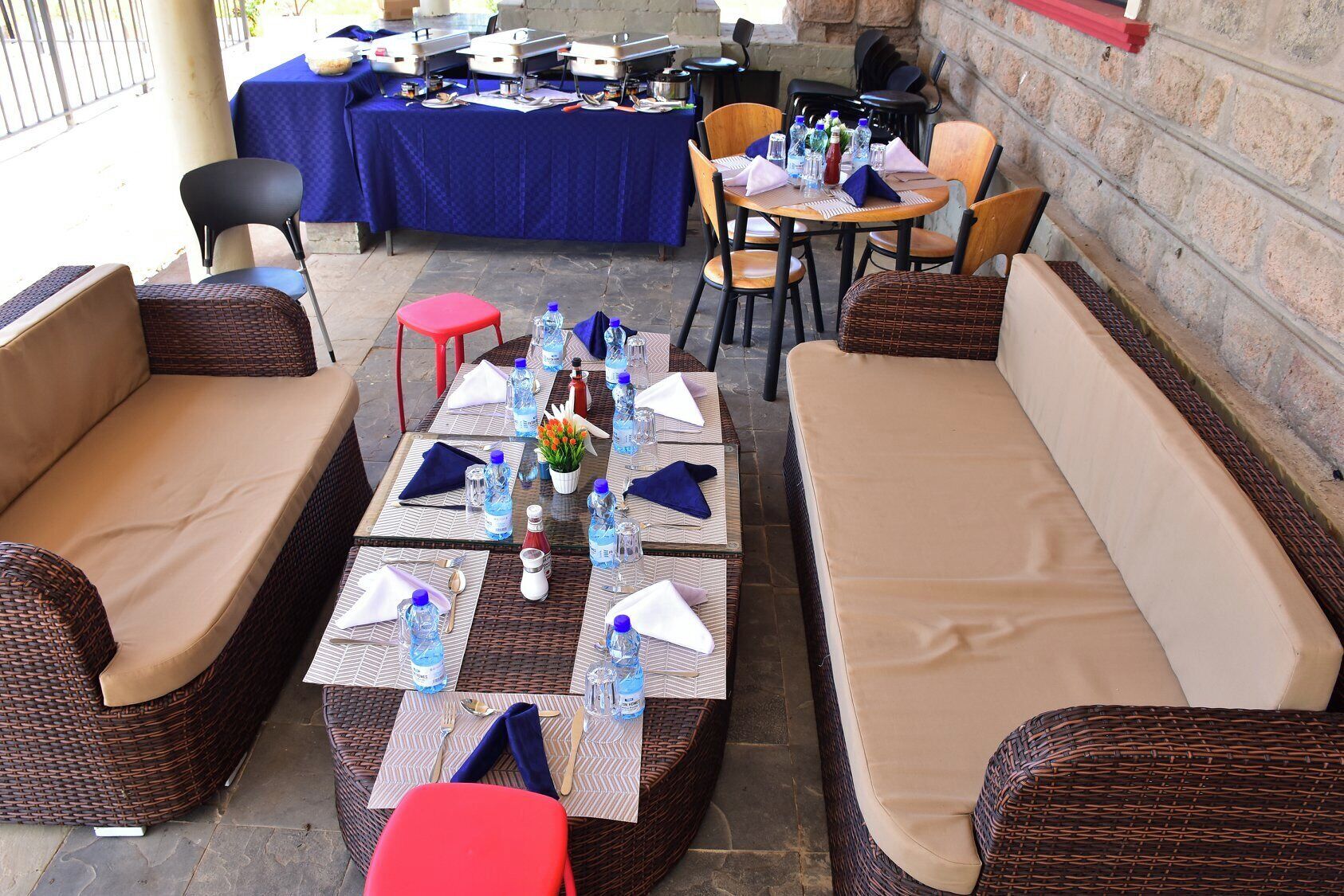 An outdoor seating area with wicker sofas and tables set up for dining.