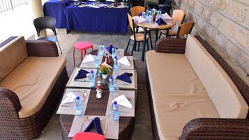 An outdoor seating area with wicker sofas and tables set up for dining.