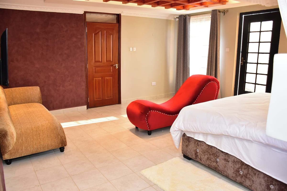Une chambre à coucher avec un lit, un fauteuil rouge et un canapé.