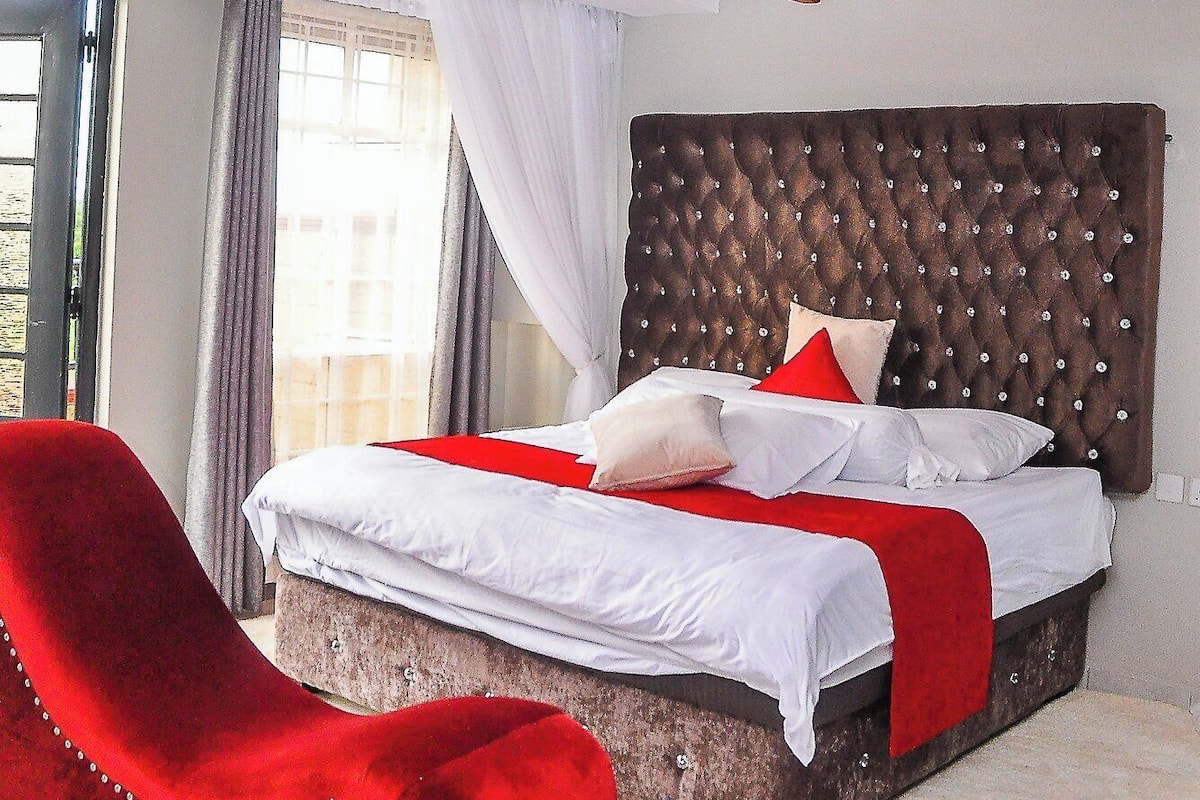 Une chambre à coucher avec un grand lit, un fauteuil rouge et un plafond à motifs.