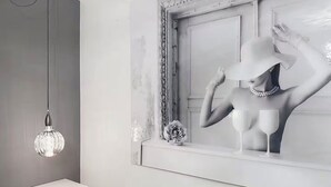 Un baño moderno con un espejo grande, una lámpara colgante y un pedestal blanco.
