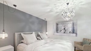 Un dormitorio moderno con una cama grande, una mesita de noche, una silla y una lámpara de techo original.