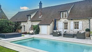 Una casa con piscina, mobiliario exterior y jardín.