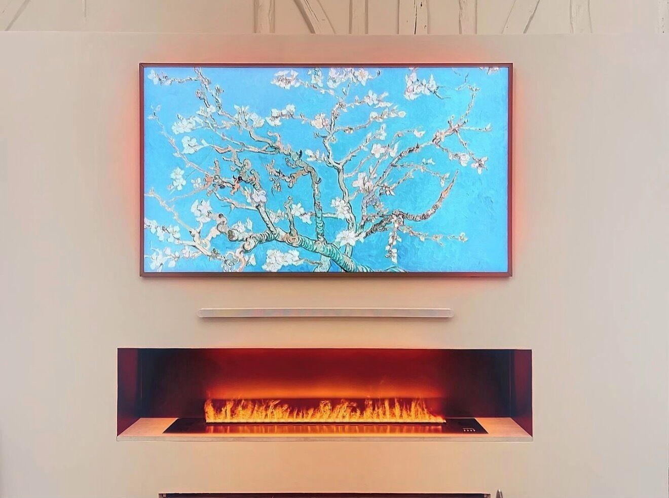 Ein Kamin mit modernem Design, darüber ein Flachbildfernseher und eine wandmontierte Steuerung.