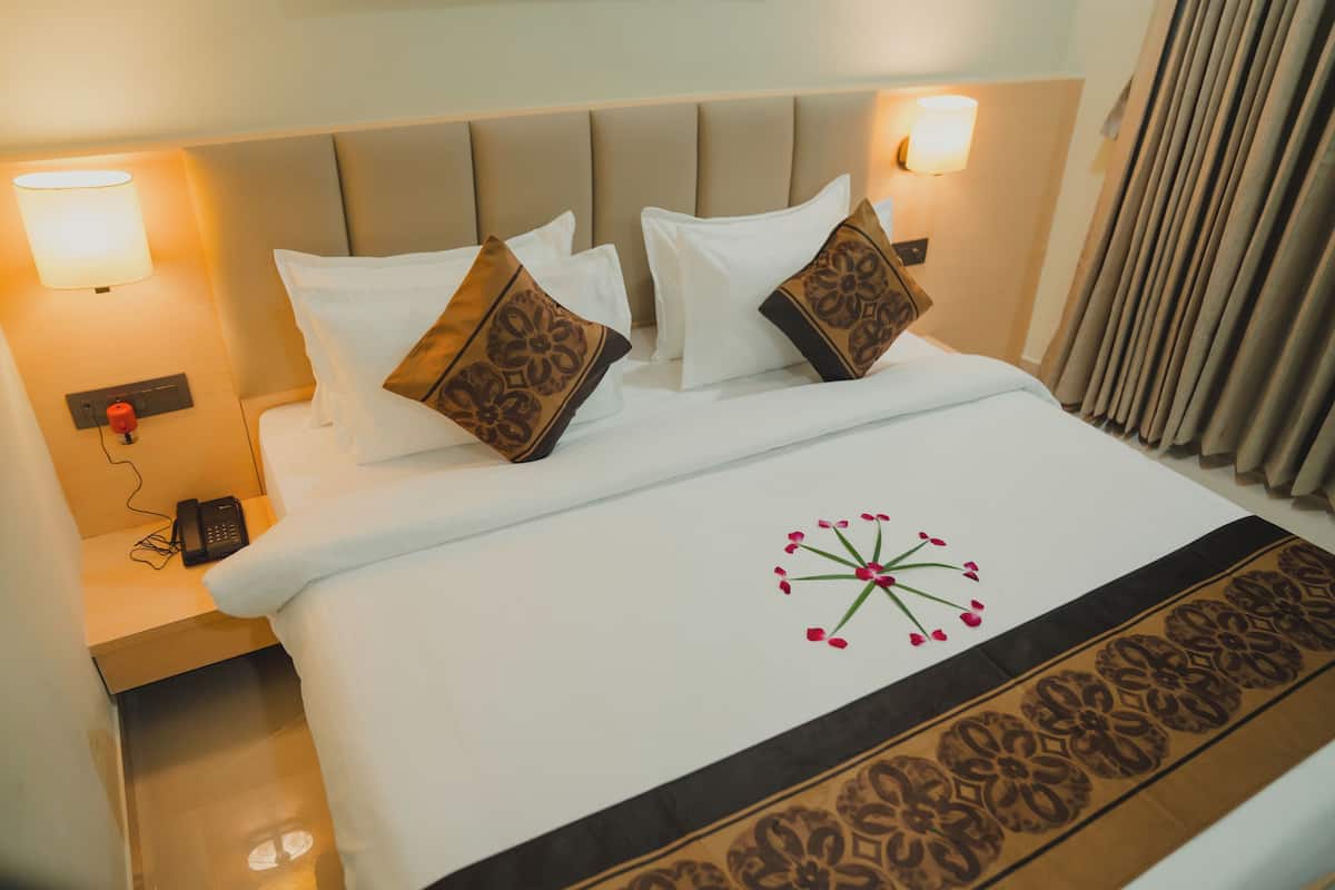A hotel room with a bed, two bedside lamps, a telephone, and a decorative floral design on the bedspread.