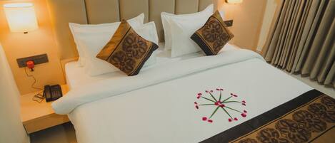 Una habitación de hotel con una cama, dos lámparas de noche, un teléfono y un diseño floral decorativo en la colcha.