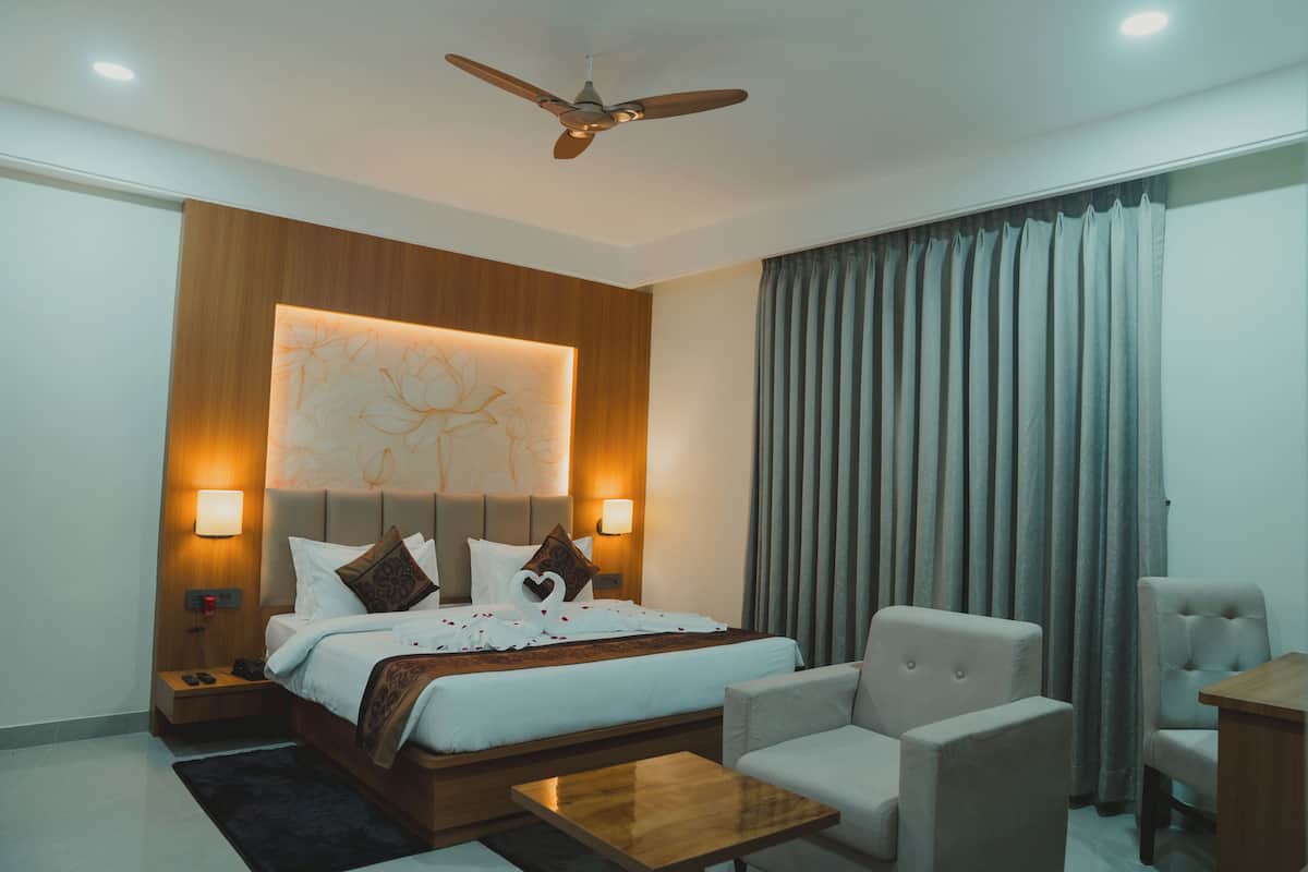 A modern hotel room with a large bed, a ceiling fan, a desk, and a chair.