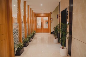 Um corredor com painéis de madeira, plantas em vasos e uma porta que dá para um quarto.
