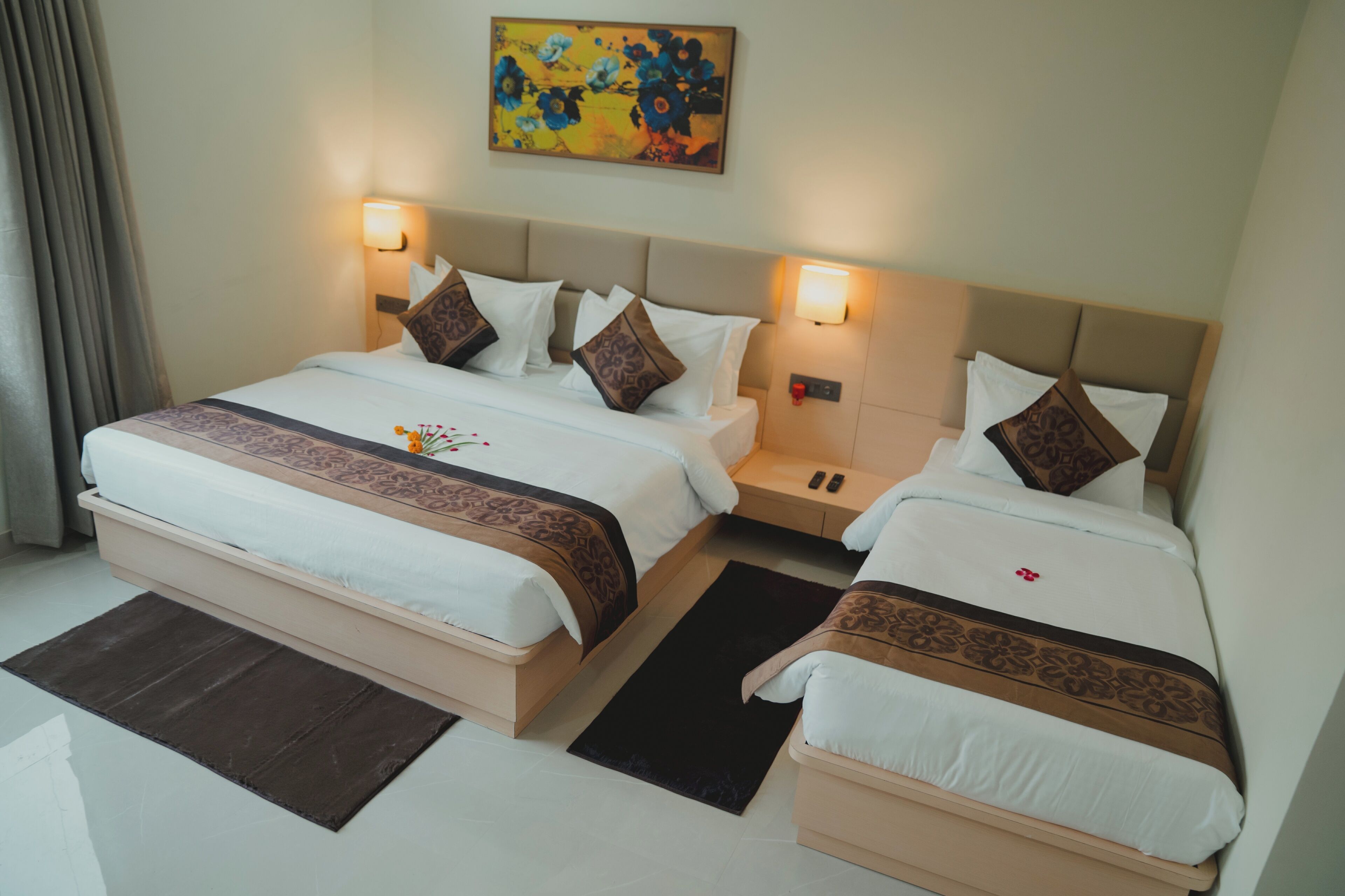 A hotel room with two beds, a nightstand, a painting, and a window with curtains.