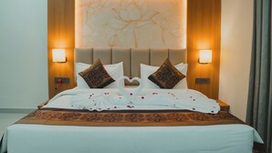 Une chambre d’hôtel avec un grand lit, deux lampes fixées au mur et une tête de lit décorative.