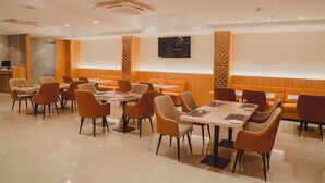 Un restaurant moderne avec des banquettes et des tables, un téléviseur à écran plat fixé au mur et un motif décoratif sur le mur.