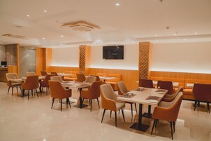 Um restaurante moderno com cabines e mesas, uma TV de tela plana na parede e um design de parede estampado.