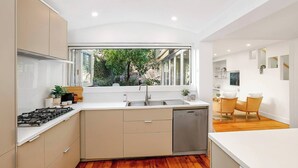 Una cocina moderna con lavavajillas integrado, estufa a gas y un amplio ventanal con vistas a la vegetación.