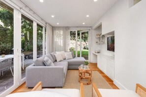 A modern living room with a grey sofa, a wooden coffee table, and a TV on the wall.