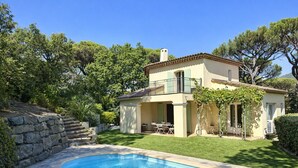 Une maison à deux étages avec une piscine, des marches en pierre et un jardin.