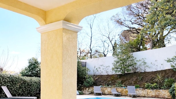Un espace de restauration en plein air avec vue sur la piscine, comprenant une table dressée pour quatre personnes, entourée de chaises au design ajouré original.
