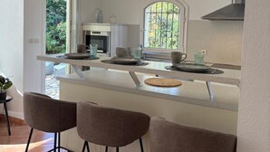 Une cuisine moderne dotée d’un îlot central, de tabourets de bar, d’un four encastré et d’une grande fenêtre.