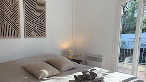 Une chambre à coucher comprenant un lit, une table de chevet, un appareil de climatisation et une vue sur l’extérieur grâce à une porte coulissante.
