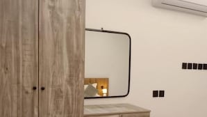 Un dormitorio con un armario de madera, una mesita de noche, un espejo y un pequeño mueble de madera.