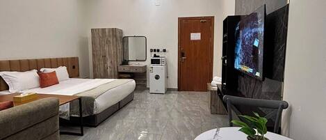 A hotel room with a bed, a sofa, a small table with a plant, a TV, and a microwave.