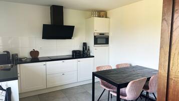 A modern kitchen with white cabinets, a black countertop, and a dining area with a table and chairs.