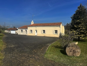 A two-story building with a tiled roof, a satellite dish, and a large tree with yellow flowers. - Le Petit Chatelier - Detached Country House With Garden in the Loire Valley (Mauges-sur-Loire)