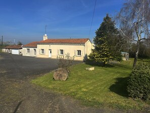 A building with a tiled roof, a chimney, and a small garden area with a stone, a tree, and a bush. - Le Petit Chatelier - Detached Country House With Large Garden in the Loire Valley (Mauges-sur-Loire)