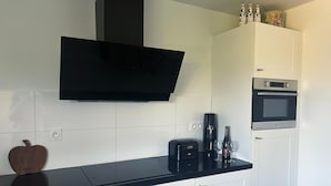 Une cuisine moderne équipée d’un téléviseur à écran plat, d’une machine à café, de verres à vin et d’un four à micro-ondes.