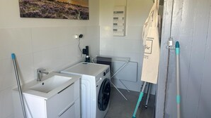 Une petite buanderie équipée d’un lave-linge, d’un sèche-linge et d’un étendoir.