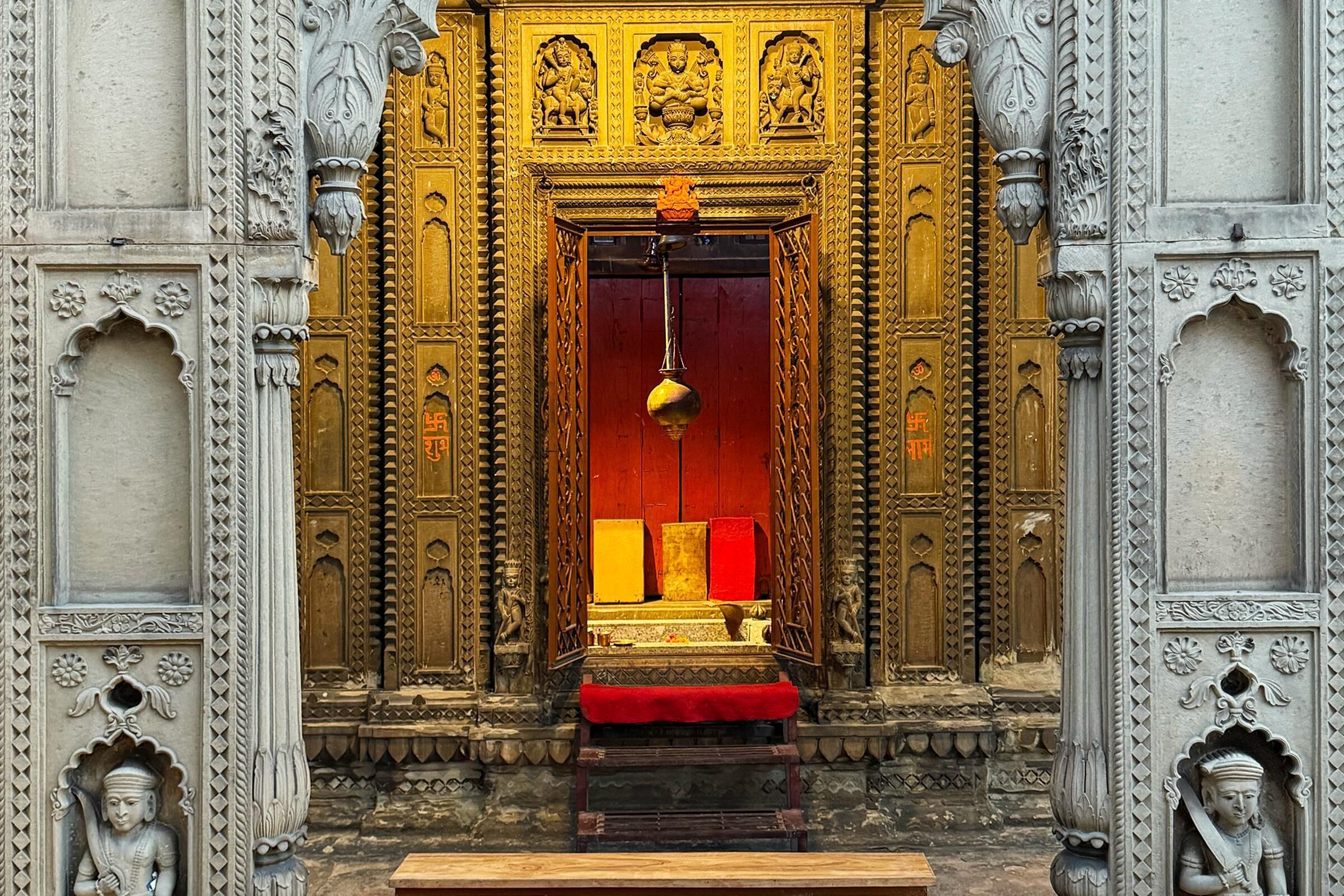 An ornate temple entrance with intricate carvings and a central red and gold structure.