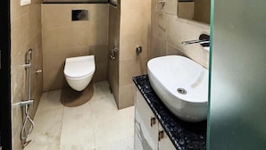 A compact bathroom with a toilet, sink, and a hand dryer mounted on the wall. - Hotel Ramya (Varanasi)