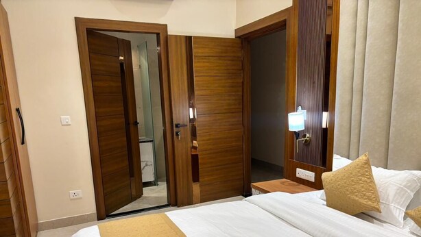 A hotel room with a large bed, wooden wardrobe, and a mirror. - Hotel Ramya (Varanasi)