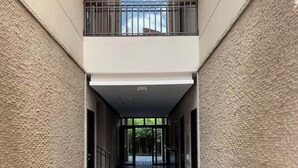 A corridor with a tiled floor leading to a balcony with a view of greenery. - Gorgeous 3-BR Condo in the heart of everything! (San Rafael de Escazú)