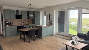 A modern kitchen with a dining area, large windows, and a view of the outdoors. - The View G03 Wyk - Sea view, terrace, garden furniture, 2nd floor, car parking (Dagebüll)