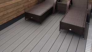 A rooftop deck with wicker furniture, a view of the sea, and a building with a sign in the background. - The View G03 Wyk - Sea view, terrace, garden furniture, 2nd floor, car parking (Dagebüll)