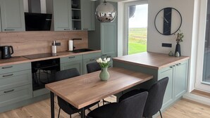 A modern kitchen with a wooden countertop, grey cabinets, and a dining area with a table and chairs. - The View G03 Wyk - Sea view, terrace, garden furniture, 2nd floor, car parking (Dagebüll)